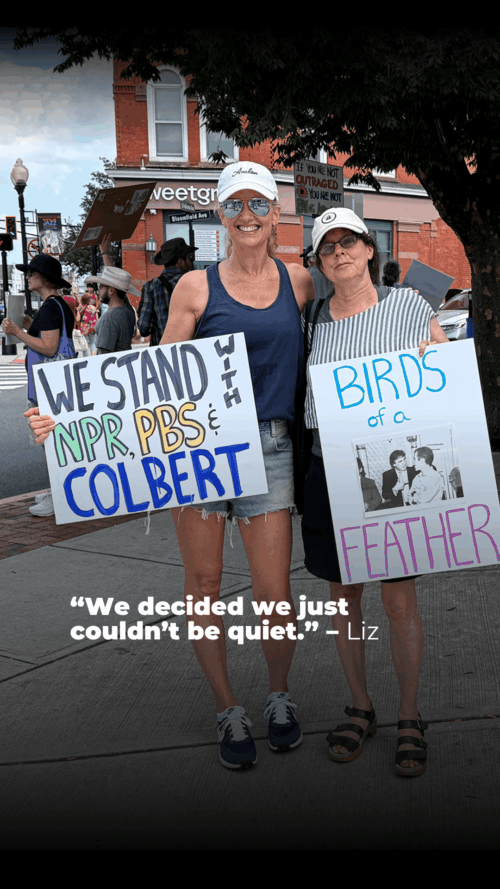 Two women smiling and holding protest signs. One reads "We stand with NPR, PBS, & Colbert," and the other reads "Birds of a Feather" with a photo. Text below says, “We decided we just couldn’t be quiet.” — Liz.